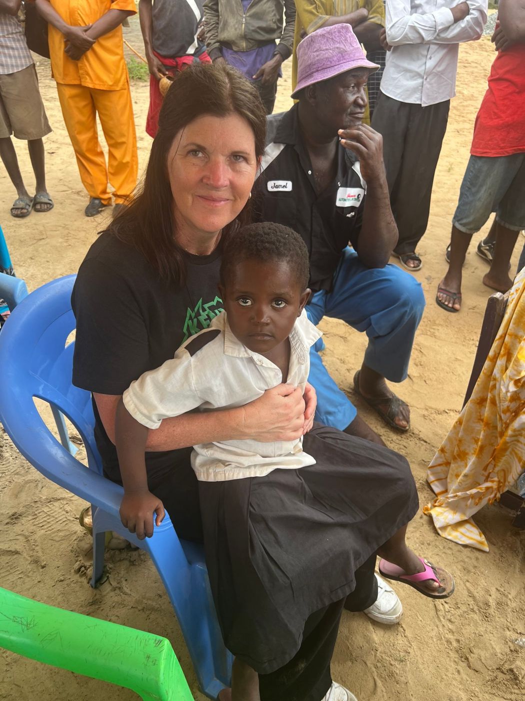 Kristin Rose holding a young student on her lap during a gathering in the village