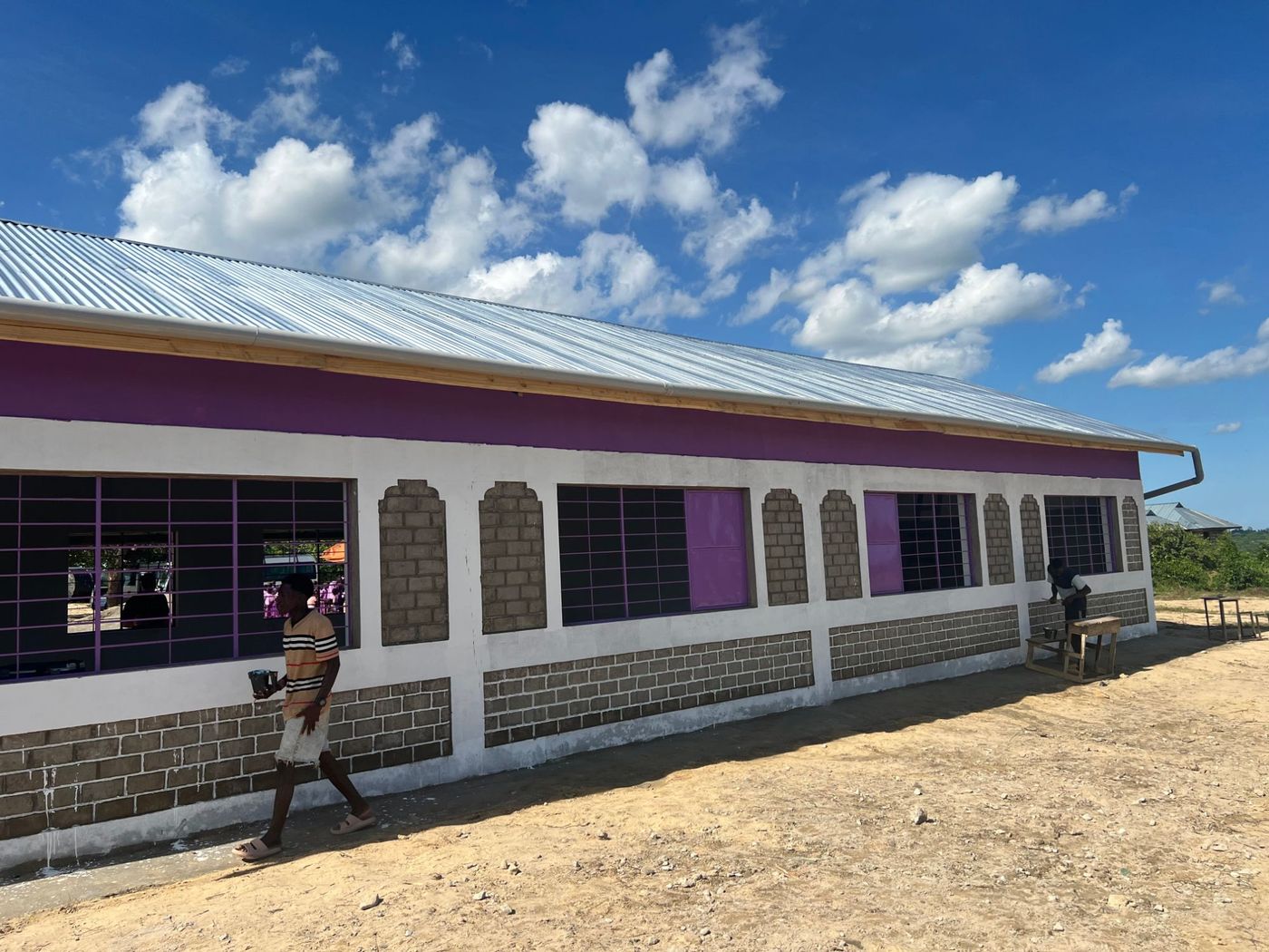 Volunteers painting the outside of a new school building